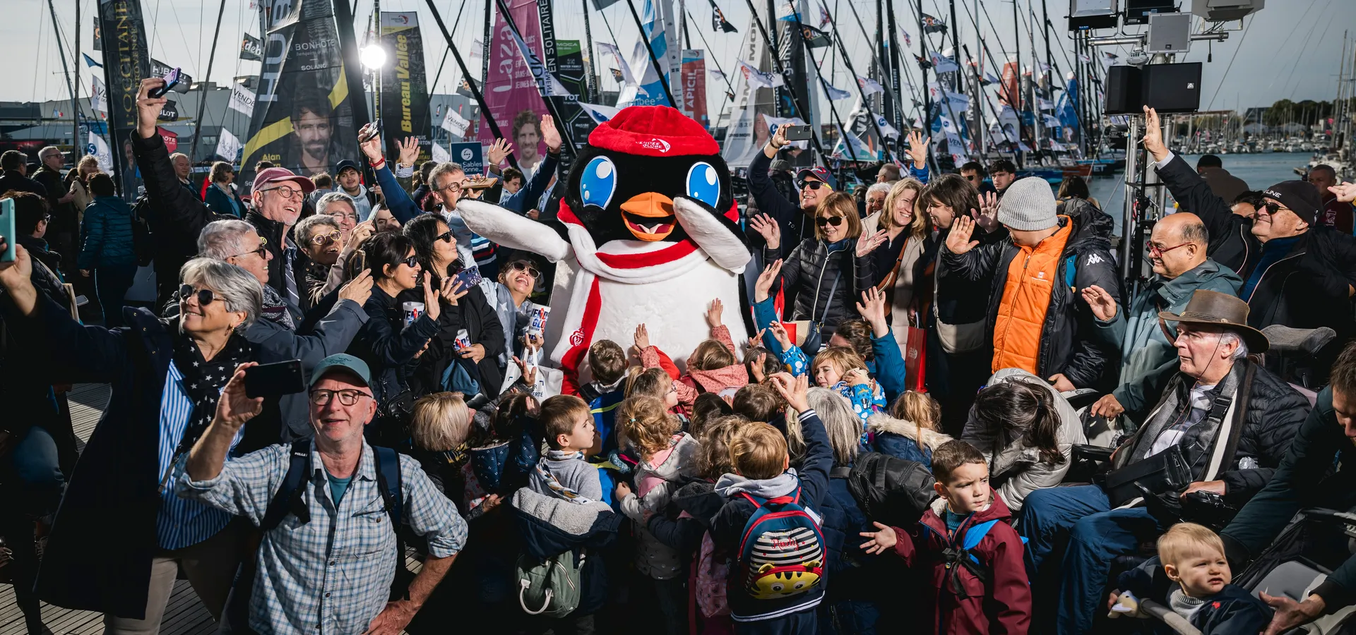 LES SABLES D'OLONNE, FRANCE - 8 NOVEMBRE 2024 : La mascotte Adélie pose avec la foule sur les pontons, dans une série spécifique de portraits réalisés lors du pré-départ du Vendée Globe, le 8 novembre 2024 aux Sables d'Olonne, France - (Photo by Jean-Louis Carli - Vincent Curutchet / Alea).