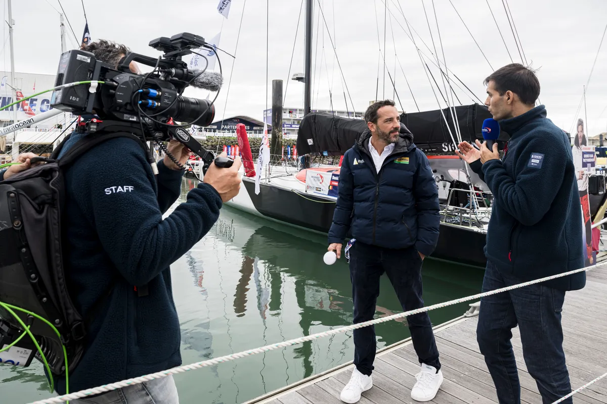 LES SABLES D'OLONNE, FRANCE - 20 OCTOBRE 2024 : Le speaker Maxime Cogny s'entretient avec le skipper de Bureau Vallée Louis Burton (FRA) et son épouse et team manager Servane Escoffier pour l'émission Vendée Live lors du pré-départ du Vendée Globe, le 20 octobre 2024 aux Sables d'Olonne, France - (Photo by Olivier Blanchet / Alea)