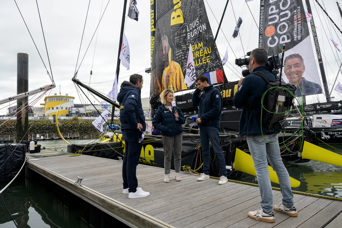 LES SABLES D'OLONNE, FRANCE - 20 OCTOBRE 2024 : Le speaker Maxime Cogny s'entretient avec le skipper de Bureau Vallée Louis Burton (FRA) et son épouse et team manager Servane Escoffier pour l'émission Vendée Live lors du pré-départ du Vendée Globe, le 20 octobre 2024 aux Sables d'Olonne, France - (Photo by Olivier Blanchet / Alea)