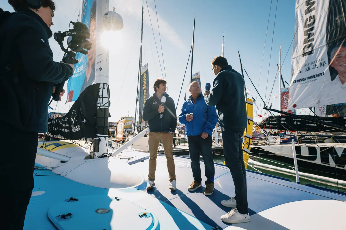 LES SABLES D'OLONNE, FRANCE - 23 OCTOBRE 2024 : Le speaker Maxime Cogny s'entretient avec le skipper de Groupe Dubreuil Sébastien Simon (FRA) pour son émission Vendée Live lors du pré-départ du Vendée Globe, le 23 octobre 2024 aux Sables d'Olonne, France - (Photo by Vincent Curutchet / Alea)