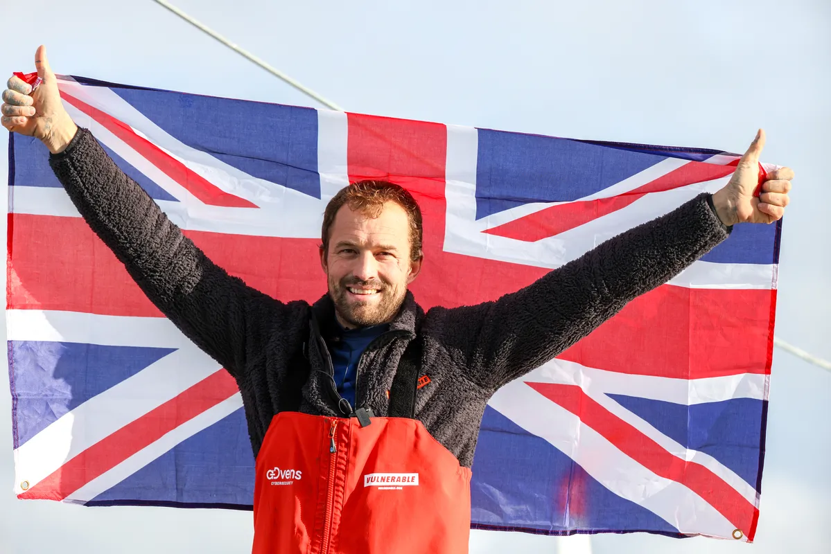 LES SABLES D'OLONNE, FRANCE - JANUARY 25, 2025 : VULNERABLE skipper Sam Goodchild (GBR) is photographed with a UK flag after taking 9th place in the Vendee Globe, on January 25, 2025 in Les Sables d'Olonne, France - (Photo by Jean-Marie Liot / Alea)