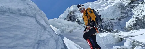 Alpiniste en doudoune jaune progressant sur une corde fixe dans une cascade de glace de l’Everest.